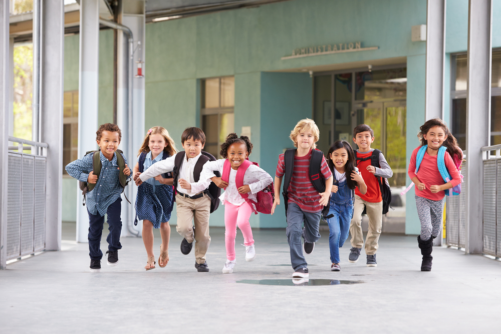 Valokuva, jossa lapset juoksee kameraa kohti koulun käytävällä.