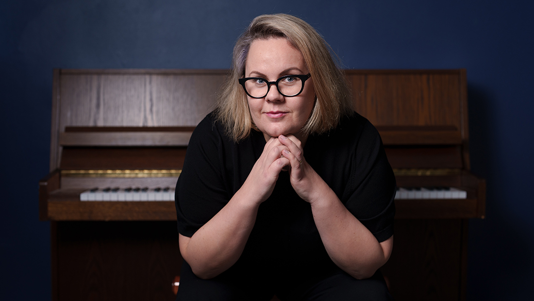 A person sitting on a chair in front of a piano.