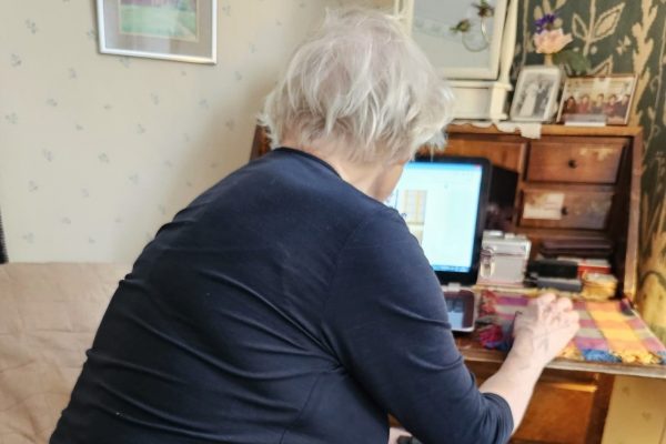 Valokuva, jossa seniori käyttää kannettavaa tietokonetta.