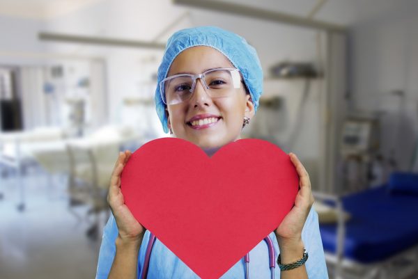 Valokuva sairaanhoitajasta, jolla on kädessä paprista tehty punainen sydän.