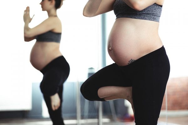 Valokuvassa kaksi raskaana olevaa voimistelee.