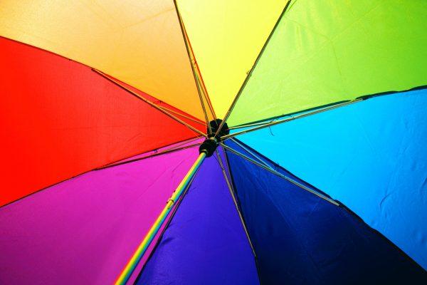 Valokuvassa sateenkaarenväreissä oleva sateenvarjo.