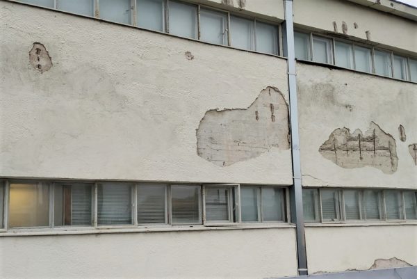 Valokuva rapatusta talon seinästä, josta rappaus on osittain kulunut pois.