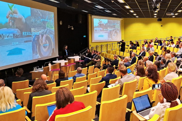 A photograph of many people sitting in a large lecture hall.